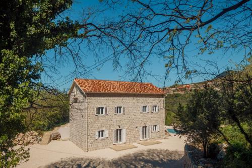 duży kamienny budynek z czerwonym dachem w obiekcie Villa Magic Stone w mieście Šišići