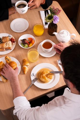 a man sitting at a table with breakfast foods and coffee at Hotel Le Six in Paris