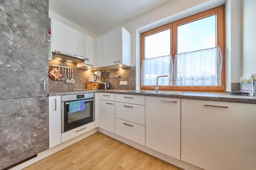 a kitchen with white cabinets and a window at Hotel Garni Tirol in Walchsee