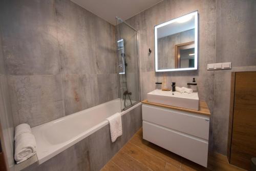 a bathroom with a tub and a sink and a mirror at Wellness Hotel Zavadilka in Prostřední Bečva