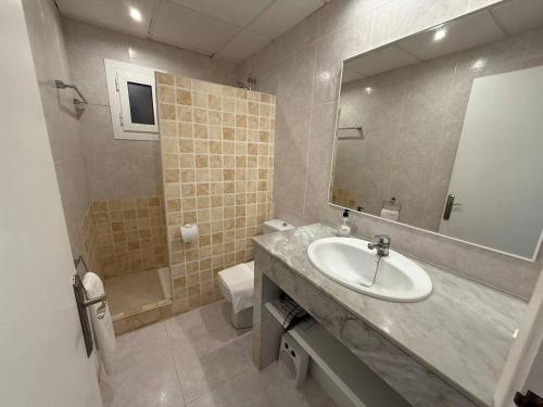 a bathroom with a sink and a mirror and a toilet at Apartamento con piscina - Posta de sol in Cala en Forcat