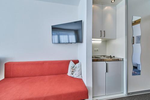 a red couch in a room with a kitchen at Hotel Garni Tirol in Walchsee