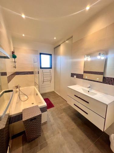 une salle de bain avec une baignoire, un lavabo et un miroir dans l'établissement Maison Terra Bella, expérience authentique en plein cœur du maquis, piscine, à Sotta