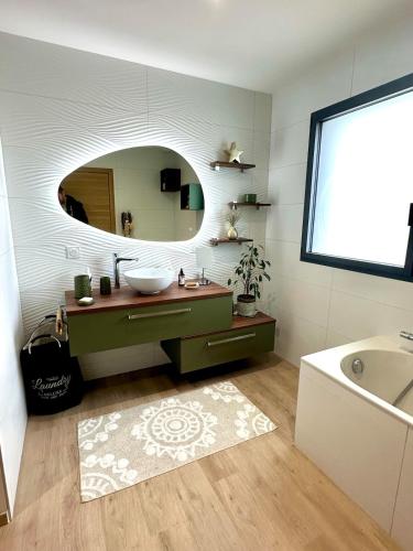 une salle de bain avec un lavabo, un miroir et une baignoire dans l'établissement Villa récente spacieuse piscine St Gilles, à Saint-Gilles-Croix-de-Vie