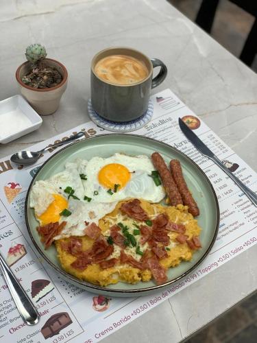 a plate of eggs and bacon and a cup of coffee at Skema Collections Quito in Quito