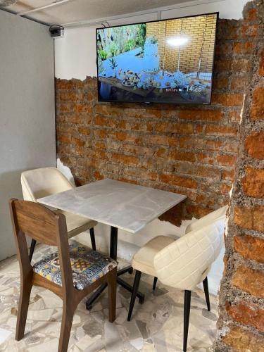 a table and chairs with a tv on a brick wall at Skema Collections Quito in Quito