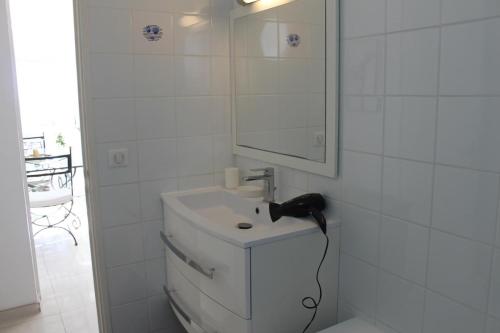 une salle de bain blanche avec un lavabo et un miroir dans l'établissement Joli t3 face mer, aux Issambres