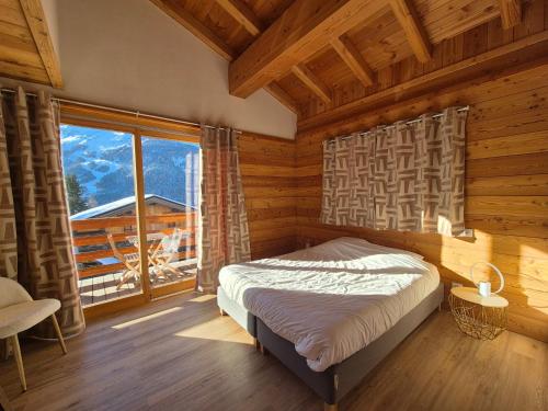 une chambre avec un lit et une grande fenêtre dans l'établissement Le Petit Chalet Villaret - App 6 pers - proche La Rosière, à Montvalezan