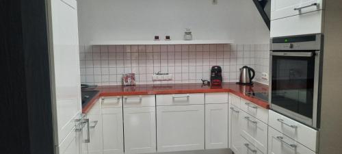 a kitchen with white cabinets and a red counter top at Loftwohnung in Hasselroth