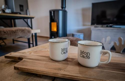 two coffee mugs sitting on top of a wooden table at Chalet Prestige aux Angles - Confort et Elégance in Les Angles
