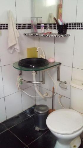 a bathroom with a toilet and a shelf with a sink at Aconchegante e familiar in Marituba