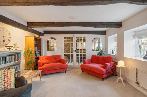 ein Wohnzimmer mit zwei roten Stühlen und einer Uhr in der Unterkunft 17th Century Cottage in Bideford Private Parking in Bideford