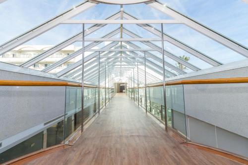 a glass corridor in a building with a glass ceiling at Eix Platja Daurada Hotel & SPA in Can Picafort
