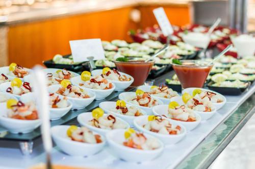 a buffet line with dishes of food on a table at Eix Platja Daurada Hotel & SPA in Can Picafort