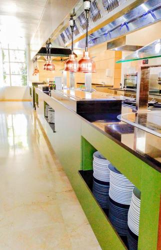 a large kitchen with a counter with plates at Eix Platja Daurada Hotel & SPA in Can Picafort