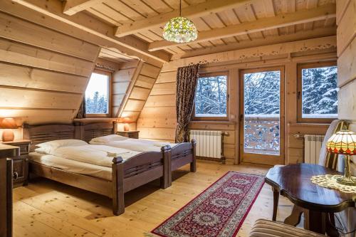 1 dormitorio en una cabaña de madera con 1 cama y 1 mesa en Góralski Spa - Luksusowa willa z sauną i wanną z hydromasażem, en Kościelisko
