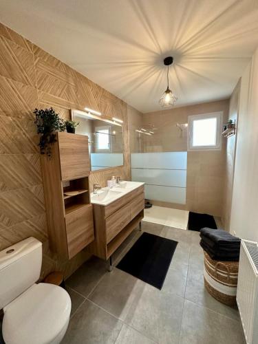 a bathroom with a sink and a toilet and a mirror at La Villa Chill in Port-en-Bessin-Huppain