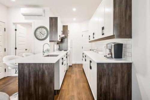 a kitchen with white cabinets and a clock on the wall at Le Mile End by M11 - Upscale 1 BDR with Sofa Bed in Montréal