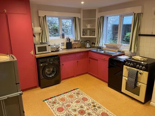 a kitchen with red cabinets and a washing machine at Lynchway in Lyme Regis