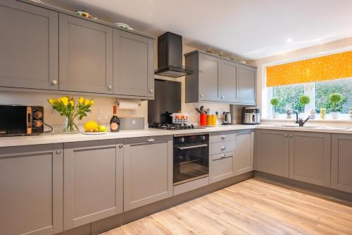 a kitchen with gray cabinets and white counters at Sunny Side - in the Heart of Beer in Beer