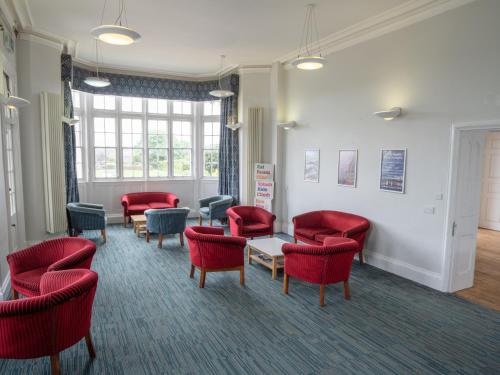 a waiting room with red chairs and a table at YHA Whitby in Whitby