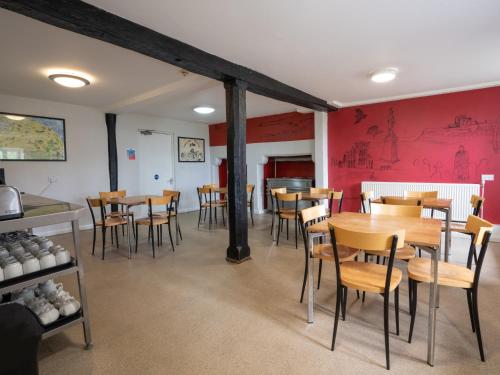 a dining room with tables and chairs and red walls at YHA Whitby in Whitby
