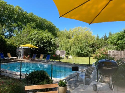 une piscine avec un grill et un parasol dans l'établissement La Pinede, à Bellegarde-du-Razès