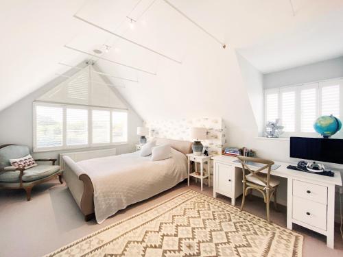 Un dormitorio con una cama y un escritorio con una computadora. en Spinneys Beachfront by The Suffolk Cottage Collection, en Thorpeness