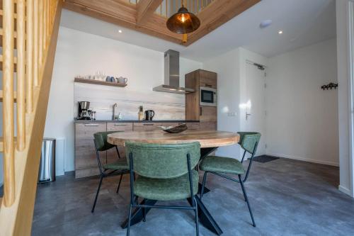 a kitchen with a wooden table and green chairs at Appartementen De Witte Brugh in Buren