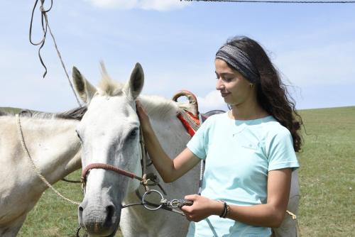 a woman standing next to a white horse at Nomad Equestrian Stable in Dzuunmod