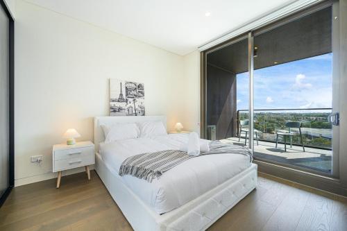 悉尼Olympic Park Stylish Apt with Gym Pool good view的卧室里有一张白色的床和一扇大窗户