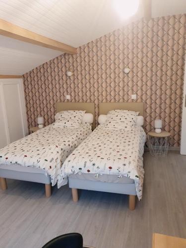 une chambre avec deux lits dans une pièce avec un mur dans l'établissement La Renardière, à Salies-de-Béarn