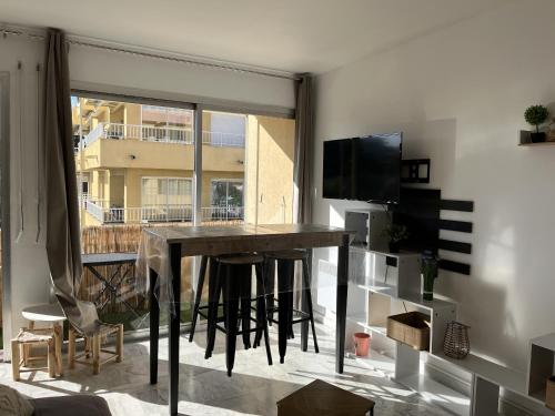 un salon avec une table et une grande fenêtre dans l'établissement le GENEPY, studio 30m2, 4 p, balcon parking, clim, à Fréjus