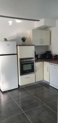 une cuisine avec des appareils électroménagers blancs et des armoires blanches dans l'établissement La Renardière, à Salies-de-Béarn