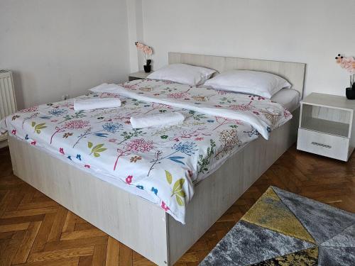 a bedroom with a bed with a floral bedspread at Apartment Zarnesti City Centre VMP Free Parking in Zărneşti