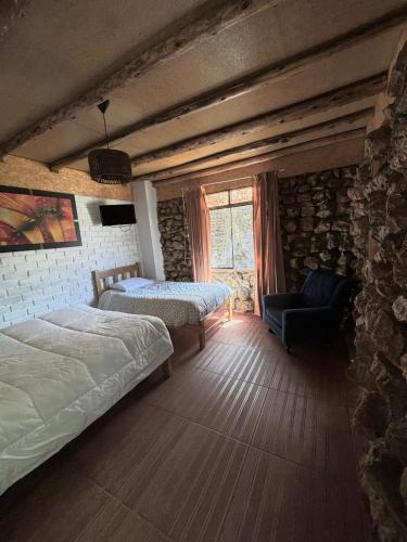 a bedroom with two beds and a stone wall at Hotel El Rancho in Concepción