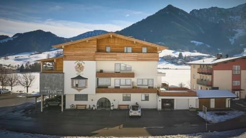 a large building with mountains in the background at Hotel Garni Tirol in Walchsee