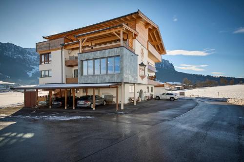 a building with cars parked in a parking lot at Hotel Garni Tirol in Walchsee