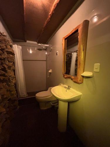 a bathroom with a sink and a toilet and a mirror at Hotel El Rancho in Concepción