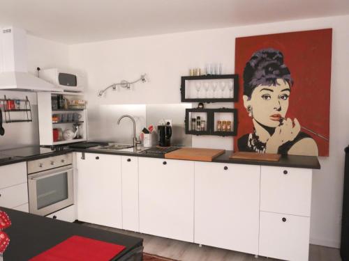 a kitchen with a painting of a woman on the wall at Appartement tout confort refait à neuf in Deauville