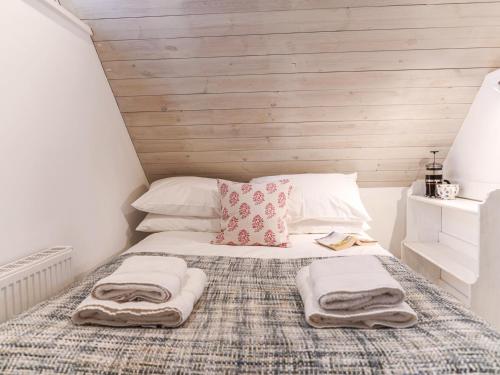 a bedroom with a bed with towels on it at Spinney's Boathouse by The Suffolk Cottage Collection in Thorpeness