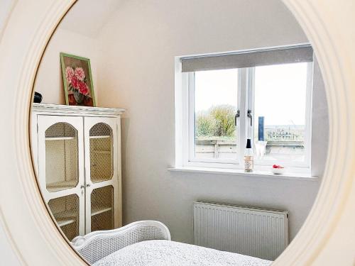 a mirror in a room with a dresser and a window at Spinney's Boathouse by The Suffolk Cottage Collection in Thorpeness