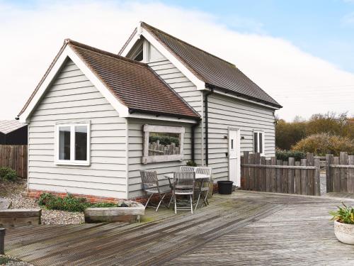 a white house with a table and chairs on a deck at Spinney's Boathouse by The Suffolk Cottage Collection in Thorpeness