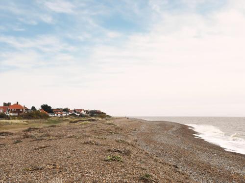 a rocky beach with houses and the ocean at Spinney's Boathouse by The Suffolk Cottage Collection in Thorpeness