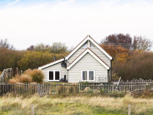 a white house with a fence in front of it at Spinney's Boathouse by The Suffolk Cottage Collection in Thorpeness