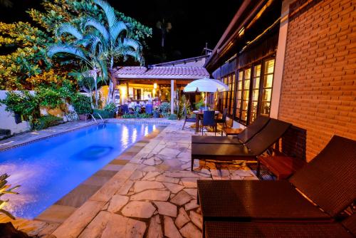 uma piscina com cadeiras e um guarda-sol ao lado de uma casa em Estalagem Casa Grande Pousada em Ubatuba