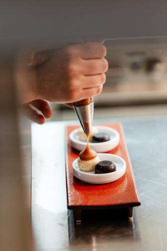 a person is pouring food into two dishes on a table at Viceroy Kopaonik Serbia in Kopaonik