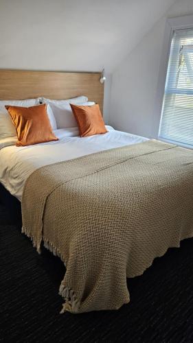 a large bed with orange pillows in a bedroom at Tommy Jacks Beach Apartments in Bude