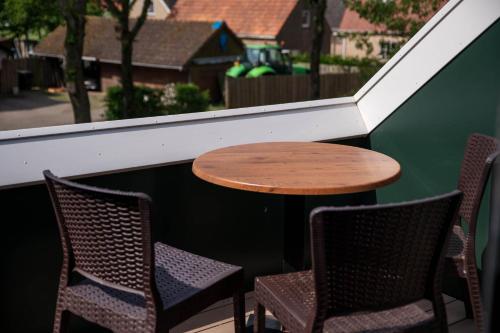 a table and chairs on a balcony with a window at Appartementen De Witte Brugh in Buren