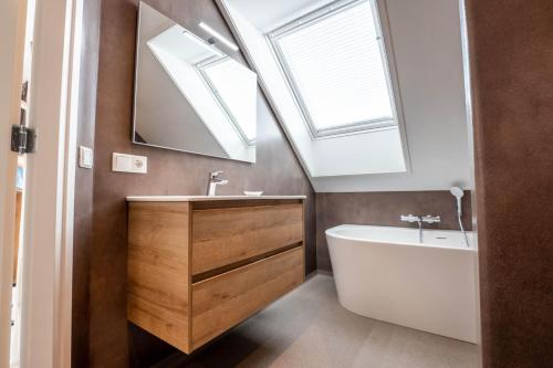 a bathroom with a sink and a tub and a mirror at Appartementen De Witte Brugh in Buren